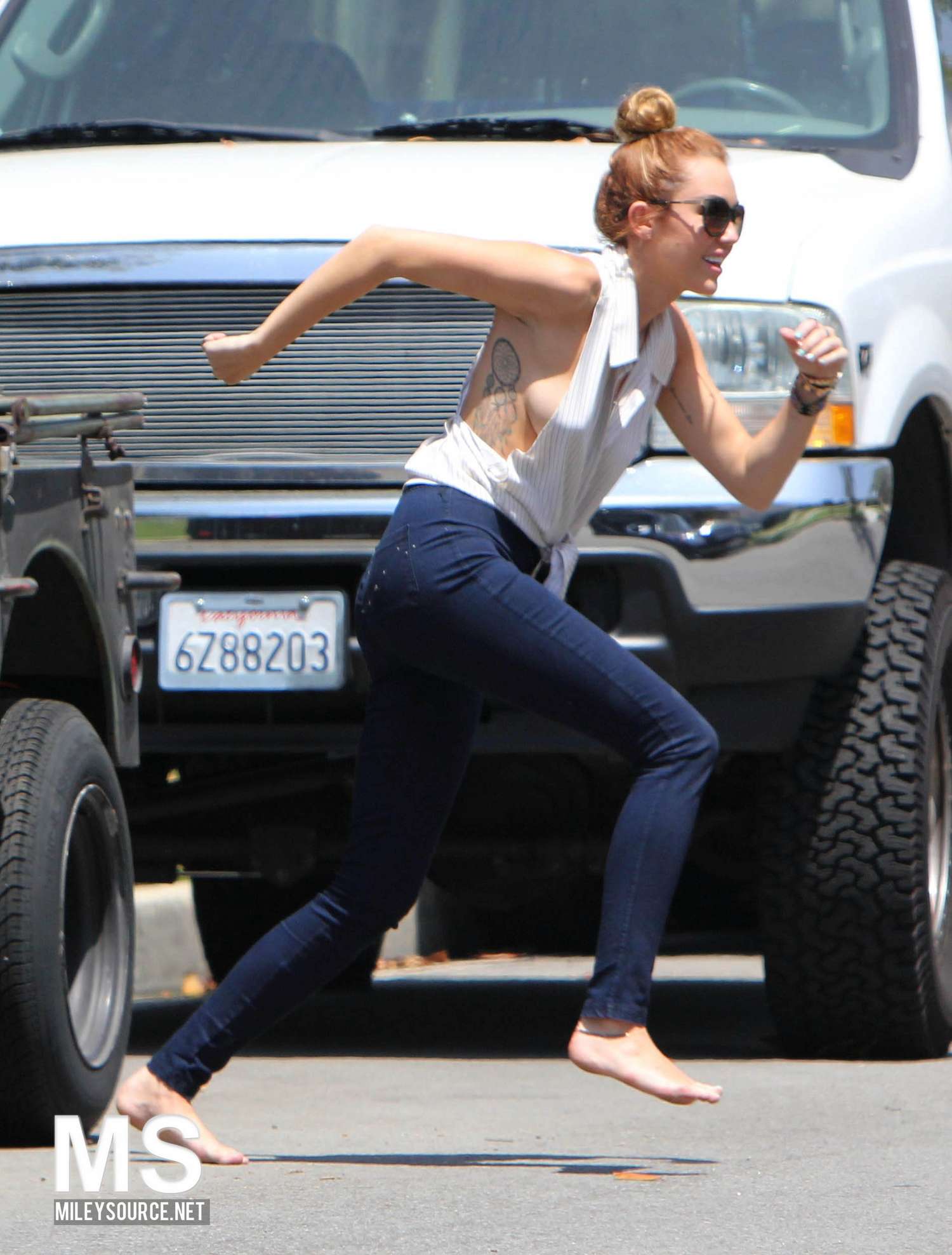 Miley Cyrus Running in a Jeans and White open top shirt in Toluca Lake